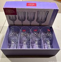 Box of four new Cristal d'Arques Longchamp wine stems visible in original purple box with glasses arranged inside