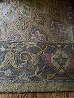 Close-up of the rug showing the intricate medallion and floral pattern with colors including light brown, gray, peach, sage, and gold.