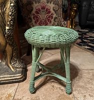 Side angle view showing the mint green rattan wicker vanity stool with four legs and X-shaped leg support structure.