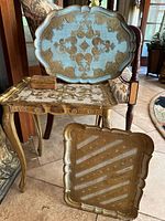 Four decorative Italian Florentine pieces arranged on and around an antique chair and table, including trays and a small box