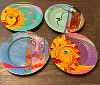 Top-down photo of the four colorful Seitu Jamaica modernist plates arranged on table showing full designs of sun and face motifs in vibrant colors.