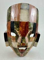 Front view of vintage Aztec Mayan tribal death mask replica made of polished semi-precious stones including mother of pearl, onyx, abalone, and more.
