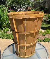 Side view of the vintage tall wood slat bushel farm basket showing its height and shape with three wooden bands securing vertical slats.