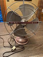 Front view of vintage Westinghouse metal propeller fan showing metal grille with brand nameplate and plastic propeller blades.