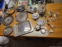 Overview of entire 26-piece silver-tone dining table accent set arranged on a wooden table.