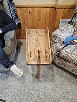 Top view of the rustic wooden slant-top stand, showing wear marks and raised edges to contain items placed on it.