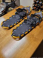 Pair of black and yellow framed snowshoes with bindings, showing top surfaces with straps