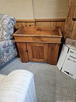 Photo of the antique dry sink showing front corner and top surface near floral sofa and cardboard boxes