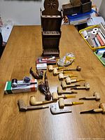 Overview of vintage pipe collection laid out on wooden table including pipes, display stand, and accessories