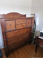 Front view of full antique solid wood dresser with seven drawers and decorative top board.