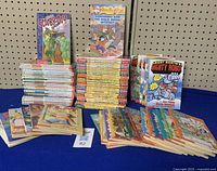 Photo showing large stacks of children's paperback books from Scooby Doo Mysteries, Geronimo Stilton, Flat Stanley, Ricky Ricottas Mighty Robot, and Jigsaw Jones series.