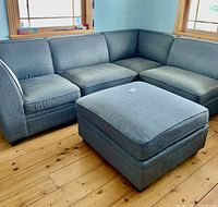 Full view of modular corner sofa set assembled with ottoman in living room.