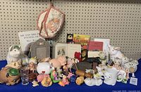Wide view of entire assortment showing variety of pig-themed items including mitts, figurines, books and kitchenware