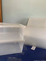 Two stacks of clear plastic storage totes showcasing the size and stacking feature, with lids visible.