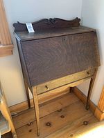 Front view of desk closed showing wood grain, carved backsplash and lock