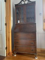 Full view of wooden secretary desk showing overall design, drawers, and flip down writing surface.