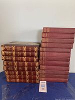 Stack of 20 hardcover books, 8 Victor Hugo and 12 Charles Reade, with maroon spines and gold embossing.