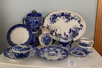 Full view of all ceramic pieces arranged including the large oil lamp, jugs, plates, and small bowls.