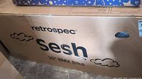 Cardboard box labeled 'Retrospec Sesh 20" BMX Bike' with cloud design, showing the product in packaging.