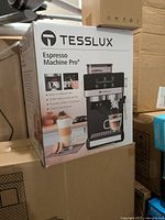Box front view showing Tesslux Espresso Machine Pro+ with built-in coffee grinder and touch control panel.