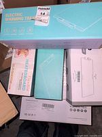 Top view of stacked boxed electric warming trays and flexible heating mats showing product packaging and labeling.