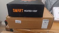 Photo of stacked boxes showing label 'Smart Heated Vest' on top box.
