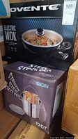Photo showing boxed Ovente electric wok and 12qt stainless steel stock pot in original packaging.