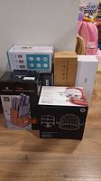 Photo showing boxed kitchen items including knives, food containers, cheese grater, warming mat, and mixer attachments