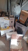 Photo showing all boxed kitchen items including grinder, chopper, range hood, cutlery set, pot holder set and meat thermometer.