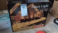 Box packaging showing product name 'Fence Light' with an image of a house decorated with string lights on the fence and roofline.