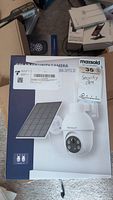 Box showing the solar security camera image and packaging, includes the solar panel and dome camera with LED lights.