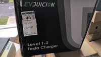 Box showing EVJucion brand and model Level 1-2 Tesla Charger labeling and Maxsold tag