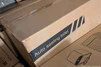 Box with label showing 'Auto sealing toilet' printed on the side, indicating the product is an auto sealing portable toilet.