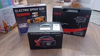 Photo showing all three boxed items: Xynover Electric Spray Gun, ZKH Impact Wrench Kit, and C3648 Battery Charger.