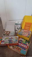 Overview photo showing all items including boxed fairy garden kit pieces, yellow educational toy box open showing items inside, flash cards box, and other boxed educational toys.