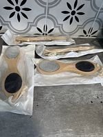 Four bamboo foot care tools displayed on a tile surface, packaged in clear plastic.