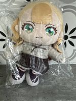 Front view of the Anima plush doll sealed in clear plastic, showing detailed face and outfit.
