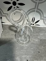Front angle view of clear glass Klein bottle showing tubular loop and hollow body