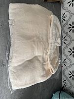 Cream-colored plush blanket sweater folded showing hood with ears and pouch pocket.