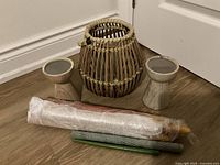 Two small wooden candle holders and one large wicker candle holder with six assorted candles.