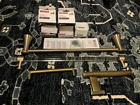 Photo showing three towel bars and some door handles and knobs on carpeted floor.