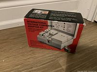 Photo of the original red and black box for the international voltage converter adaptor kit showing some wear.