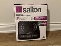 Front view of boxed Salton portable induction cooktop showing product image and features