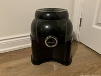 Front view of the glossy black Primo water dispenser showing its smooth curved design and Primo logo badge on front.