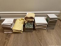 Photo showing four distinct stacks of small square tiles including white, decorative with leaves, off-white, and gray textured types.