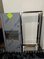 Photo of the paper towel dispenser with protective film and the stainless steel disposal unit side by side.