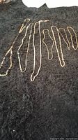 Seven gold tone chains displayed on a black fabric background showing various lengths and styles.