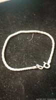 Silver rock chain bracelet laid flat on a black surface showing chain links and clasp