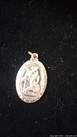 Photo of sterling silver St. Christopher medal pendant on black background.