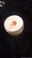Single faceted orange Mexican fire opal gemstone placed on white foam for display.